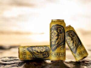 A chilled Scarface beer can placed on a wooden table with condensation, emphasizing its bold branding and strong, premium appeal
